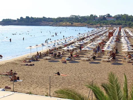Das flache Wasser des A'-Strands von Voula voller Menschen an einem Sommertag