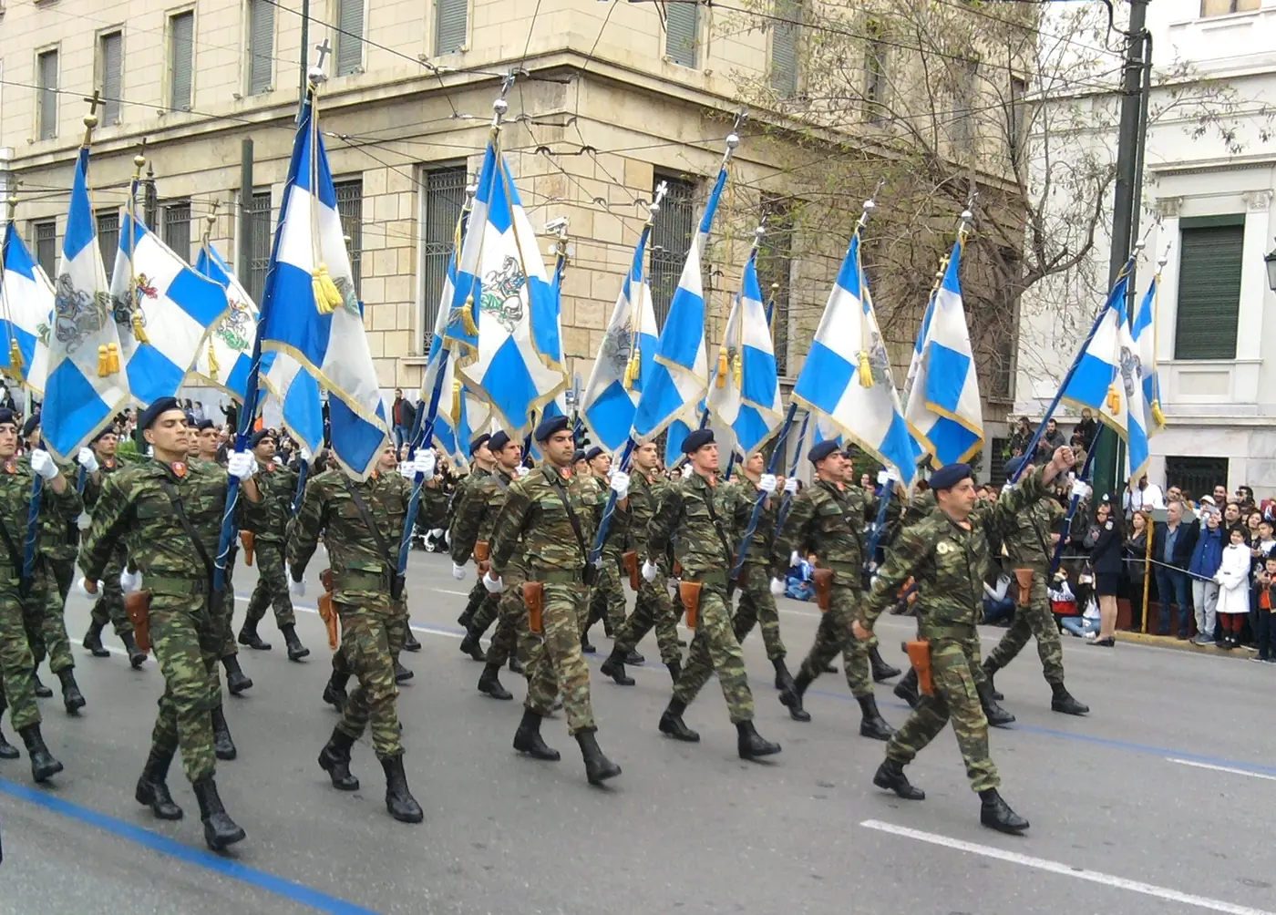Στρατιώτες με σημαίες παρελαύνουν στη Βασιλίσσης Αμαλίας με κόσμο στο πεζοδρόμιο, 25 Μαρτίου