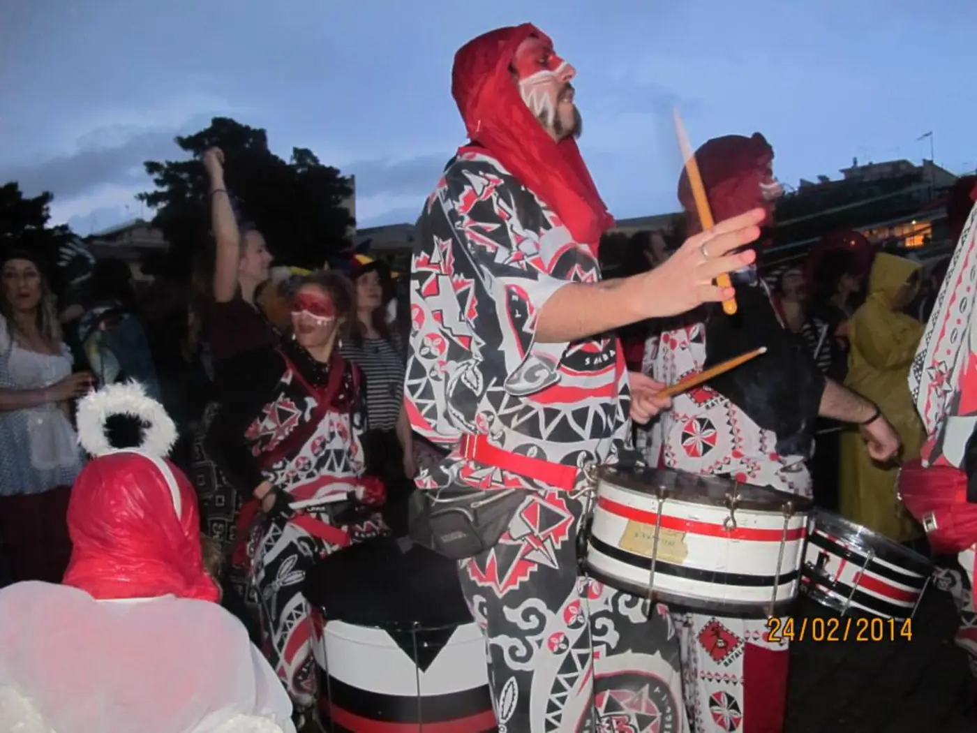 Tambour en turban rouge et costume à motifs géométriques jouant au milieu de la foule
