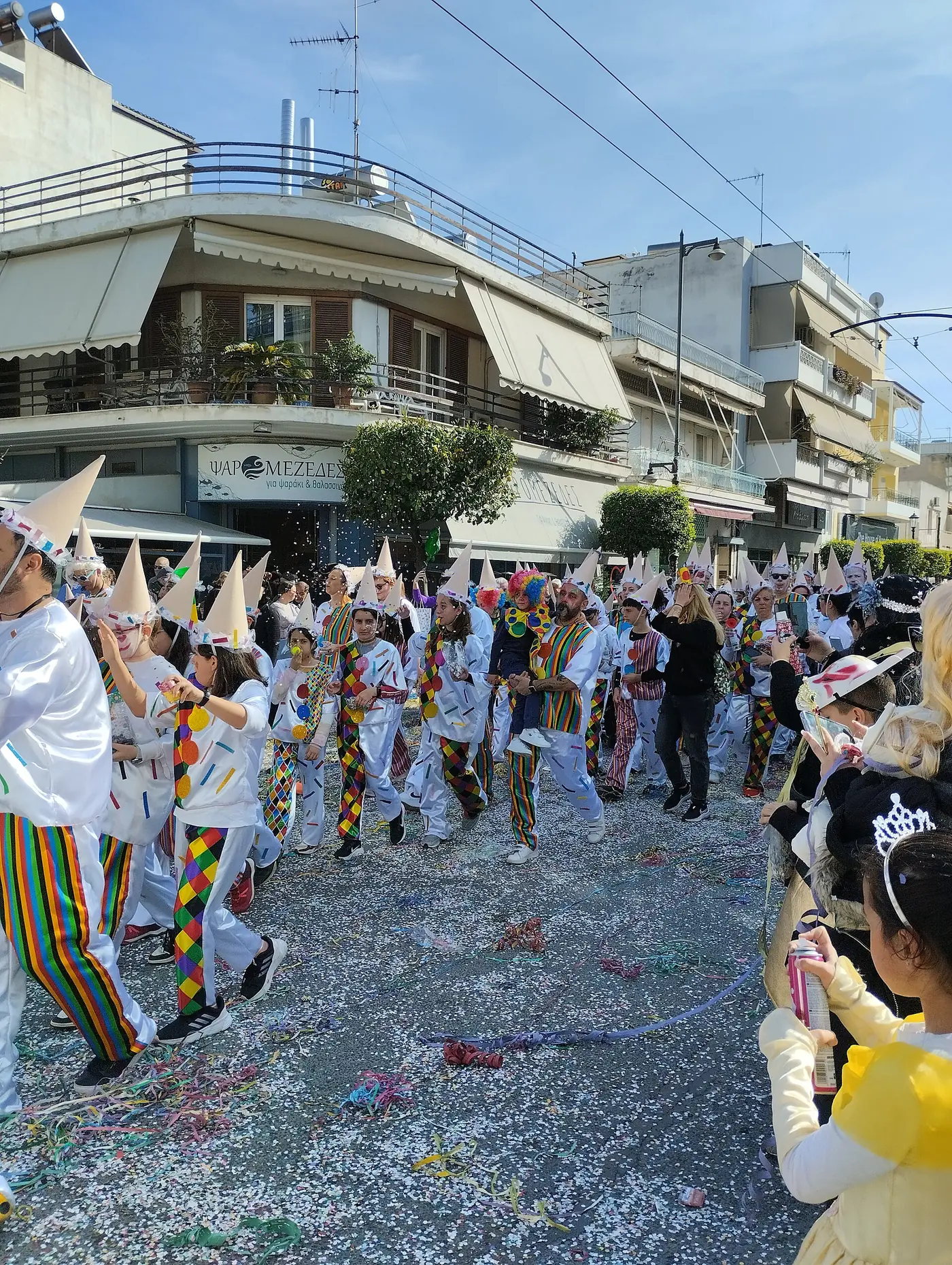 Défilé avec confettis dans l’air et carnavaliers en chapeaux entre des immeubles à Moschato