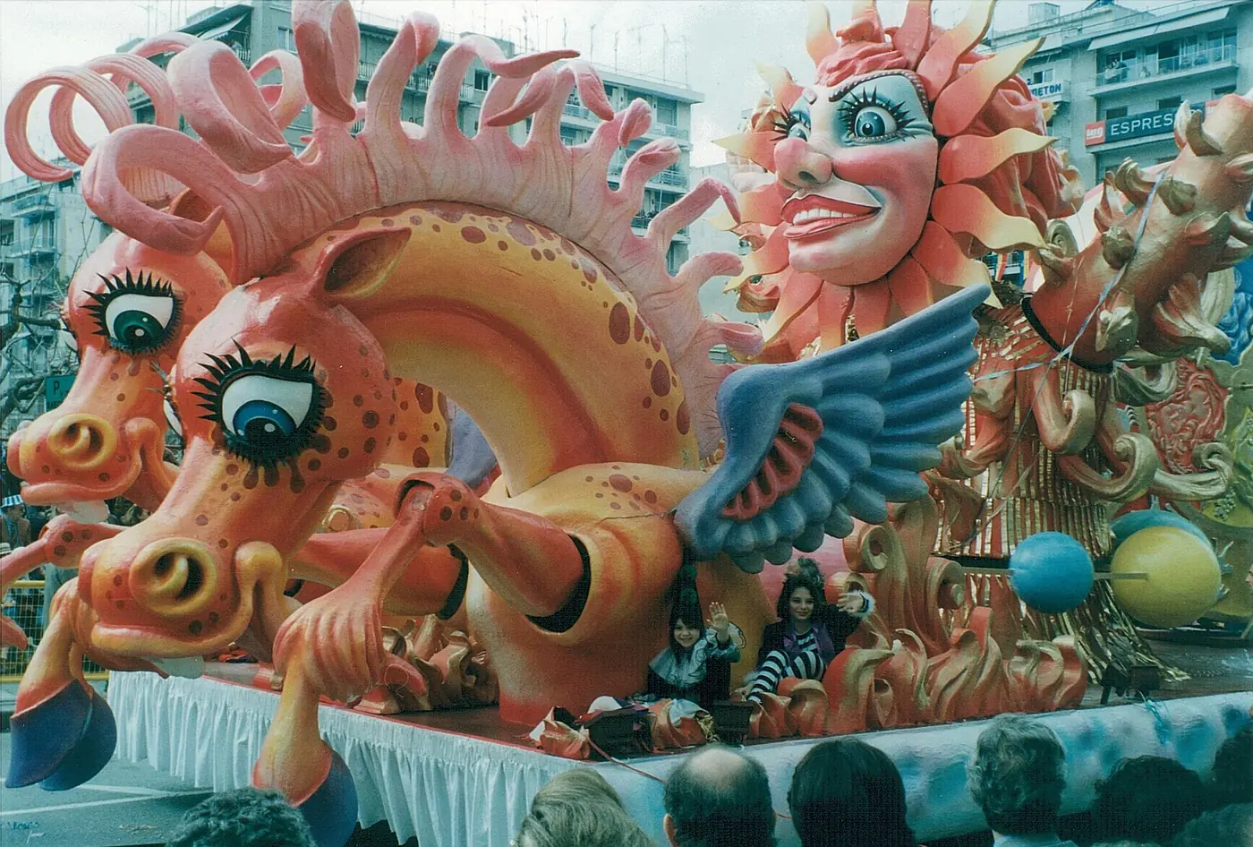 Char avec deux grands visages de soleil et des ailes en bleu et orange au carnaval de Patras de 1995