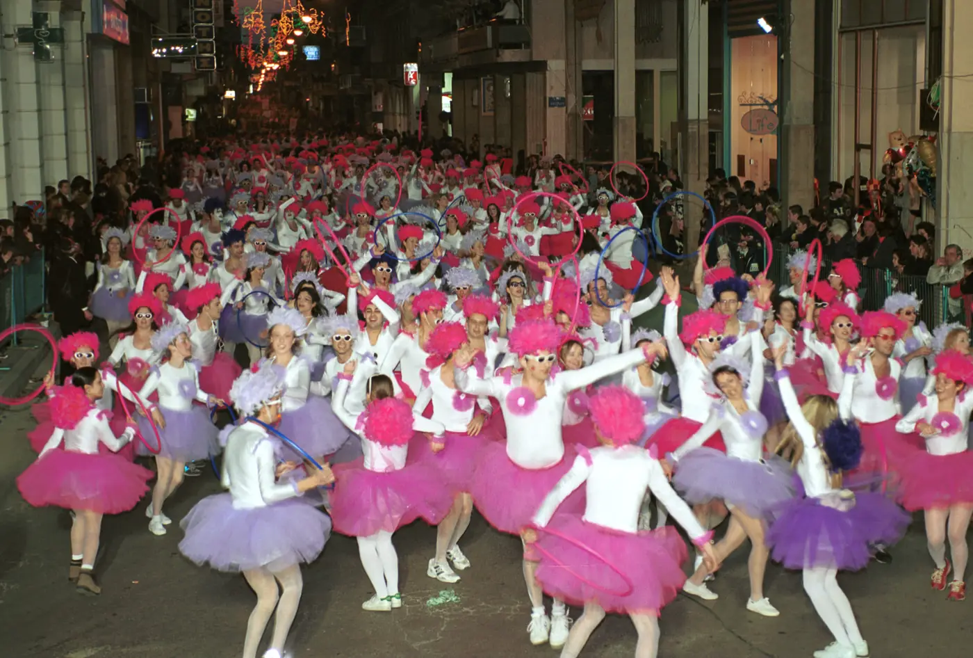 Défilé nocturne à Patras avec des filles en tutus roses dansant dans une rue illuminée