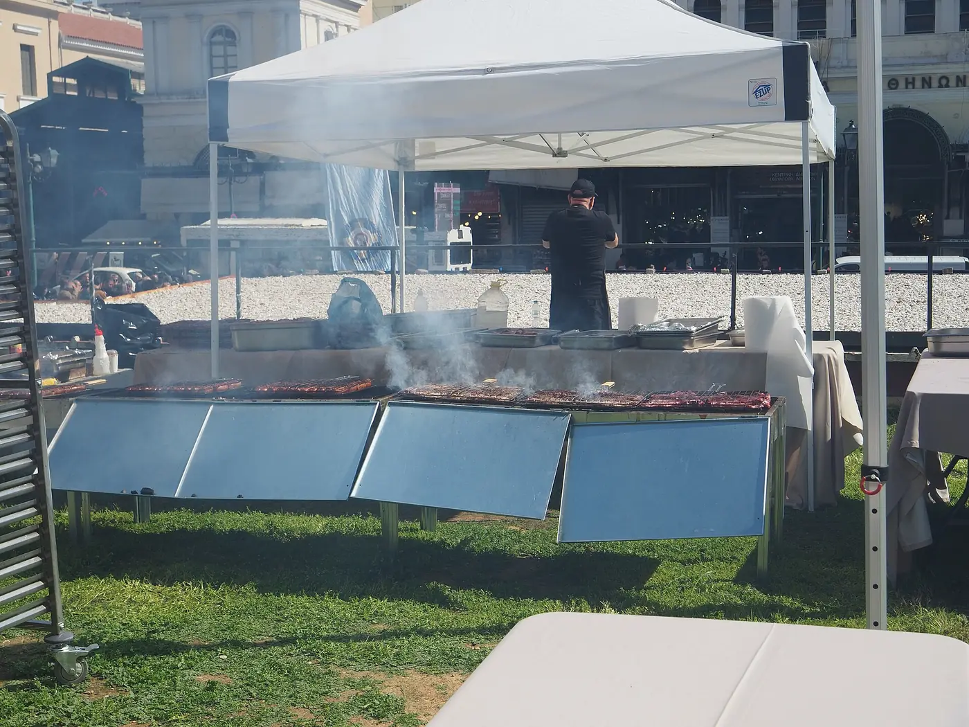 Μεγάλη ψησταριά με κάρβουνα κάτω από λευκή τέντα στη Βαρβάκειο την Τσικνοπέμπτη, με μαγείρους να ψήνουν