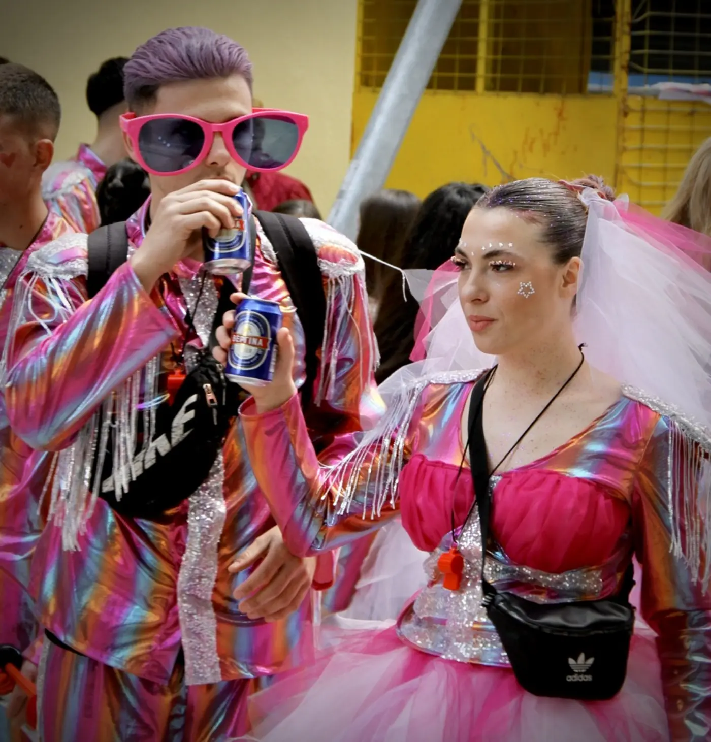 Deux jeunes en costumes rayés colorés, lunettes de soleil roses et voile blanc au défilé du carnaval de Xanthi