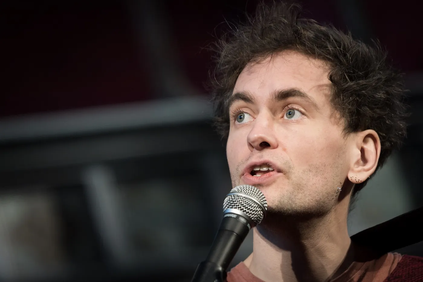 Alabaster DePlume spricht ins Mikrofon, aus der Nähe, vor dunklem Hintergrund