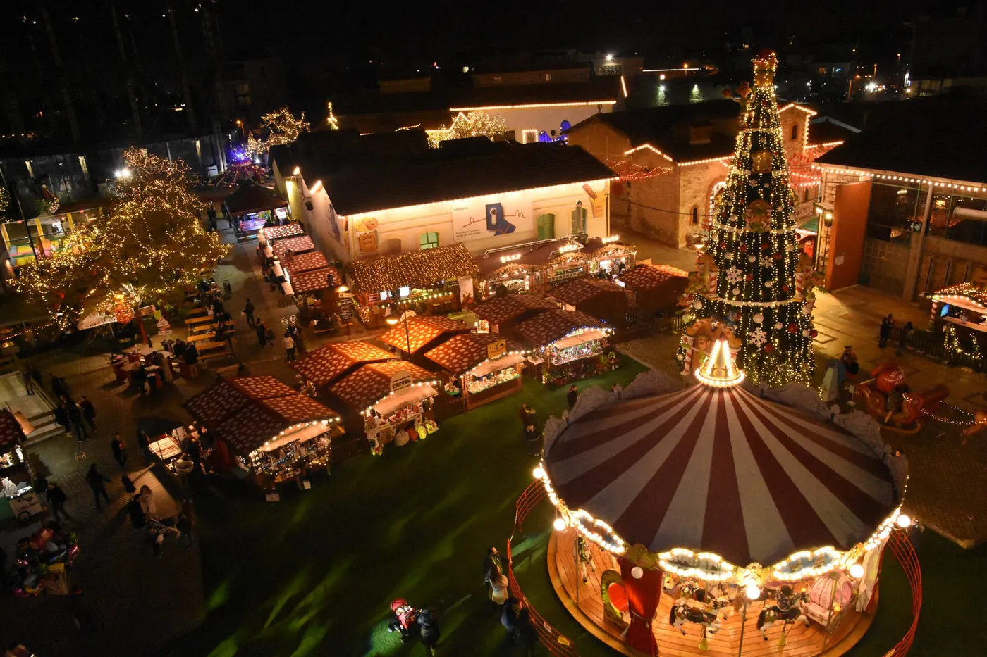 Die Technopolis nachts von oben, mit beleuchteten Gebäuden, Ständen und einem großen Weihnachtsbaum