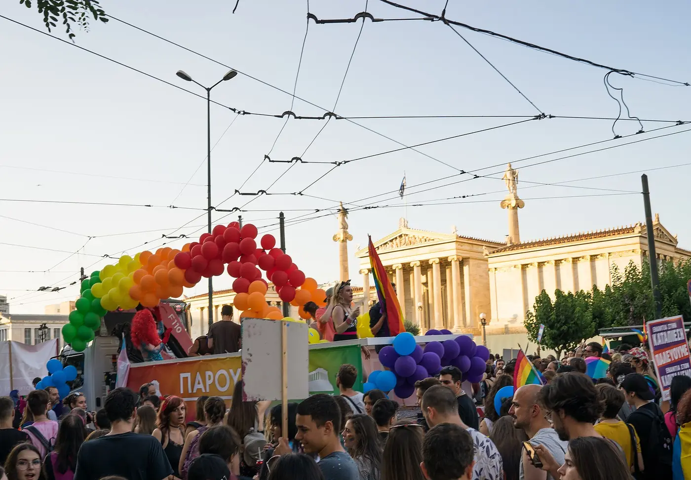 Платформа с арка от балони в цветовете на дъгата пред Атинската академия, заобиколена от хора