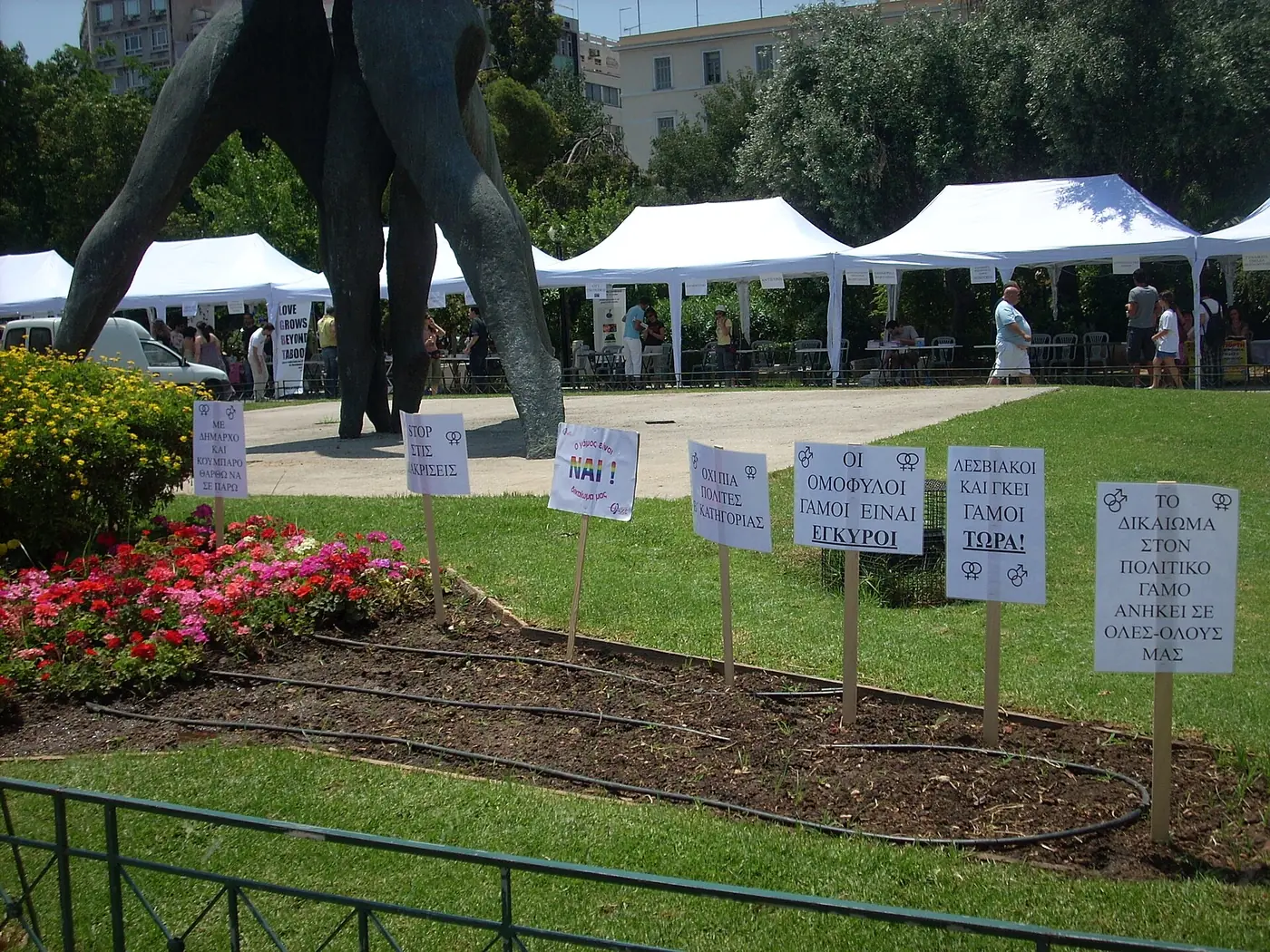 Бели шатри на щандове и табели на тревата на площад Клафтмонос на Athens Pride през 2009 г.