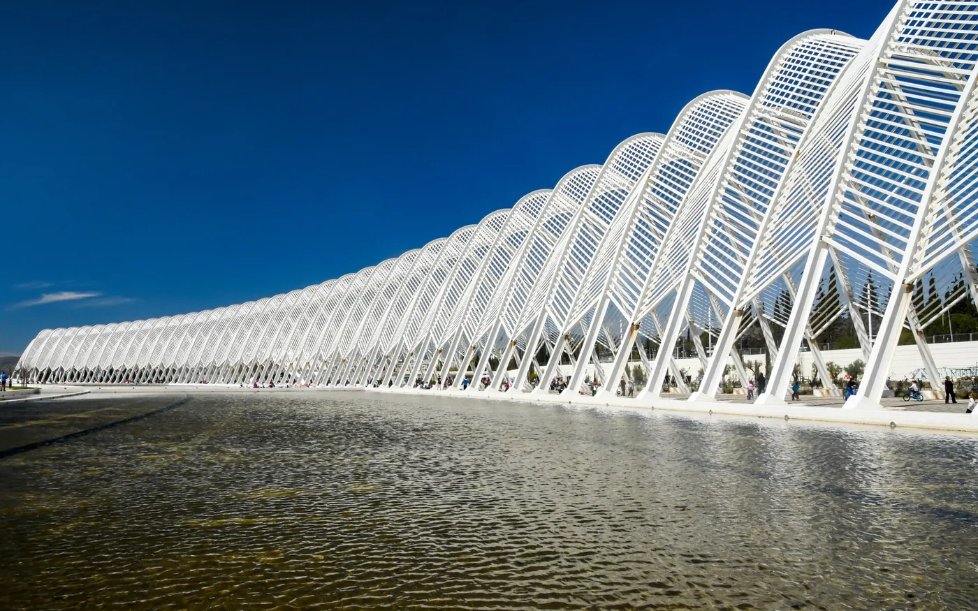 Les arches blanches en acier de Calatrava à l’OAKA, avec de l’eau devant et un ciel bleu