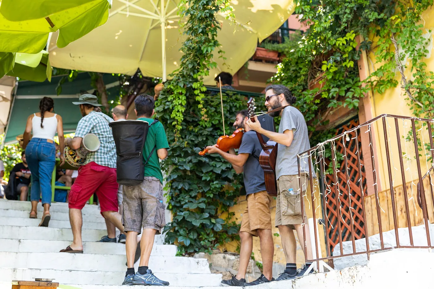 Músicos callejeros con violín y guitarra en unas escaleras de Plaka, con gente subiendo a su lado