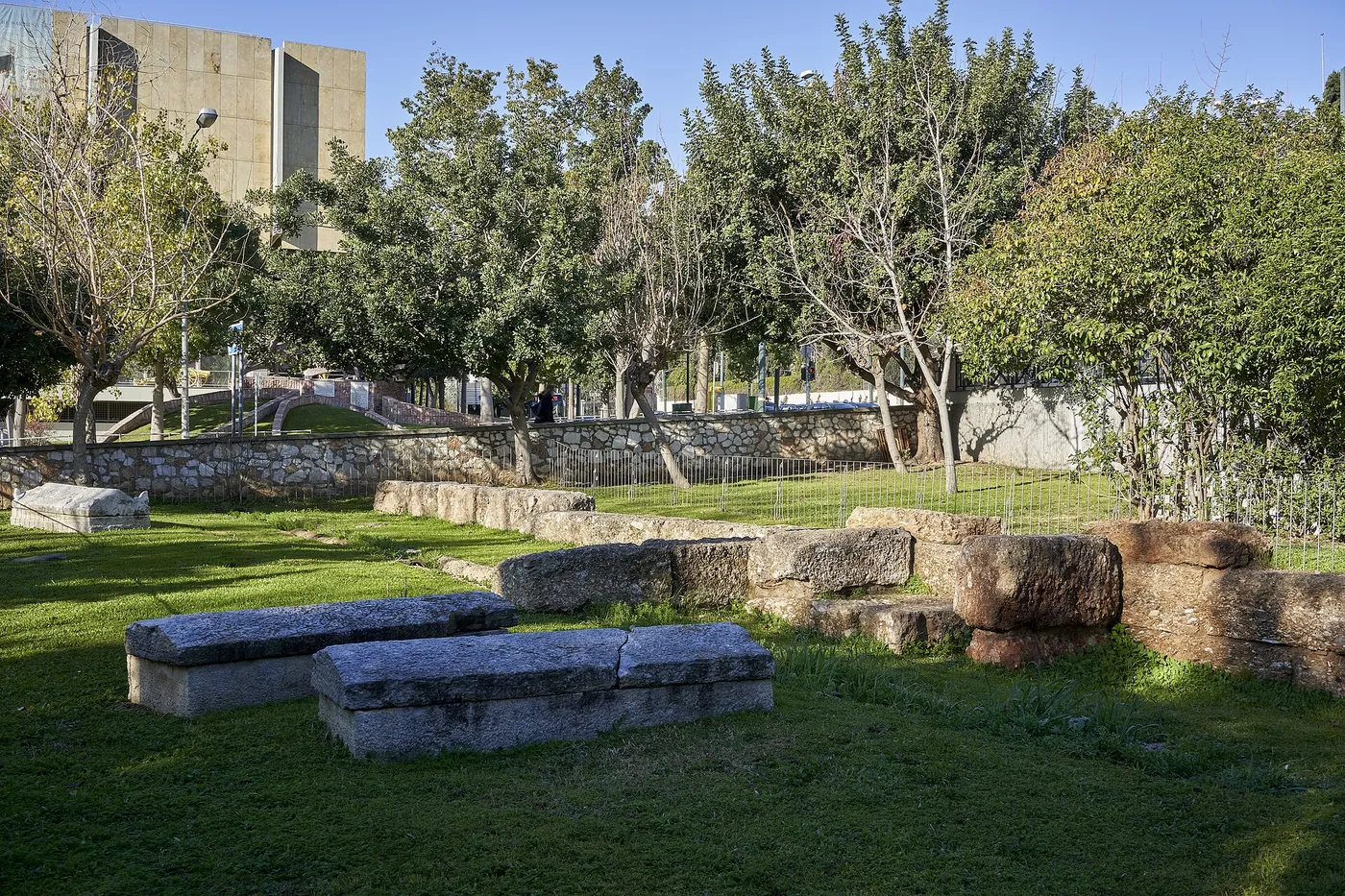 El parque Rizari con césped, árboles y fragmentos de mármol antiguos