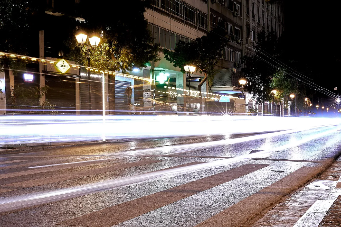 Η οδός Σταδίου τη νύχτα με φανοστάτες και φώτα αυτοκινήτων σε λευκές γραμμές