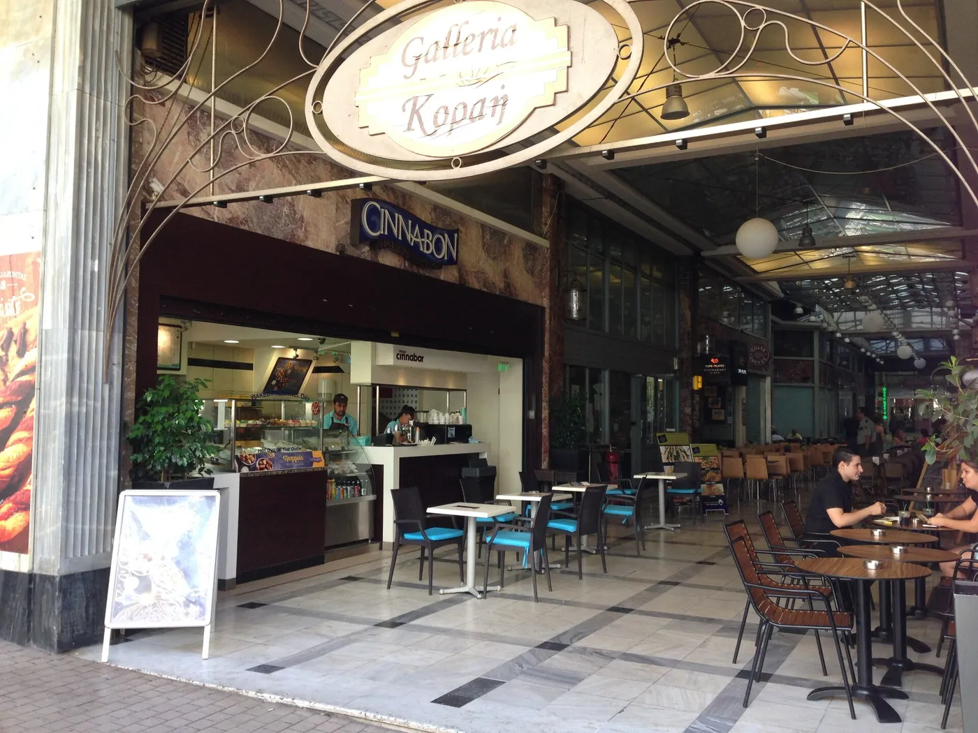 Η είσοδος της Στοάς Κοραή με την επιγραφή Galleria Κοραή και τραπεζάκια καφέ μέσα στη στοά