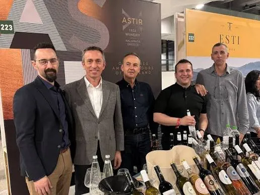 Des gens d’un domaine à leur stand, avec bouteilles et verres sur le comptoir