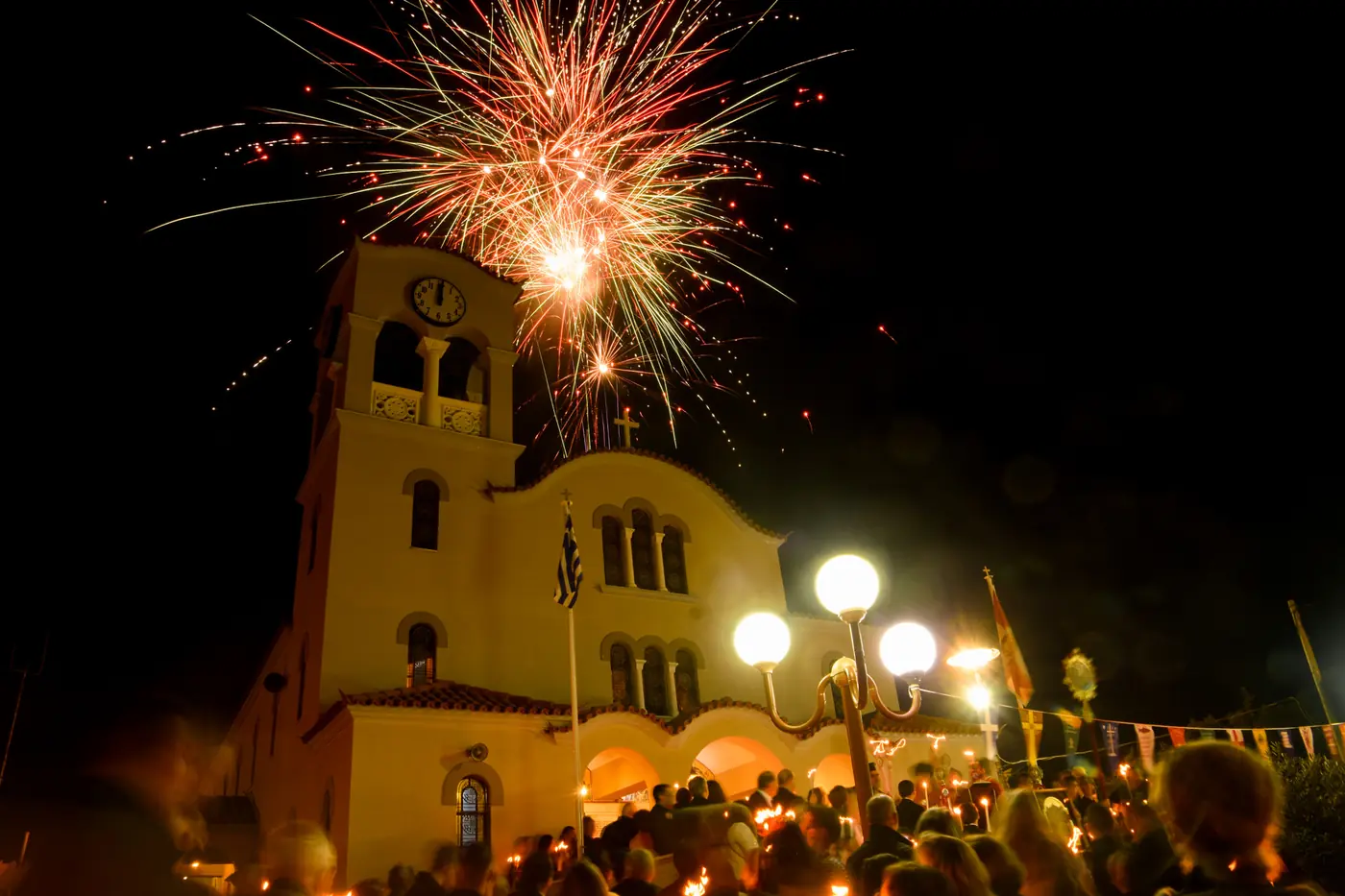 Feux d’artifice au-dessus du clocher d’une église à minuit à Pâques, avec la foule aux cierges sur la place