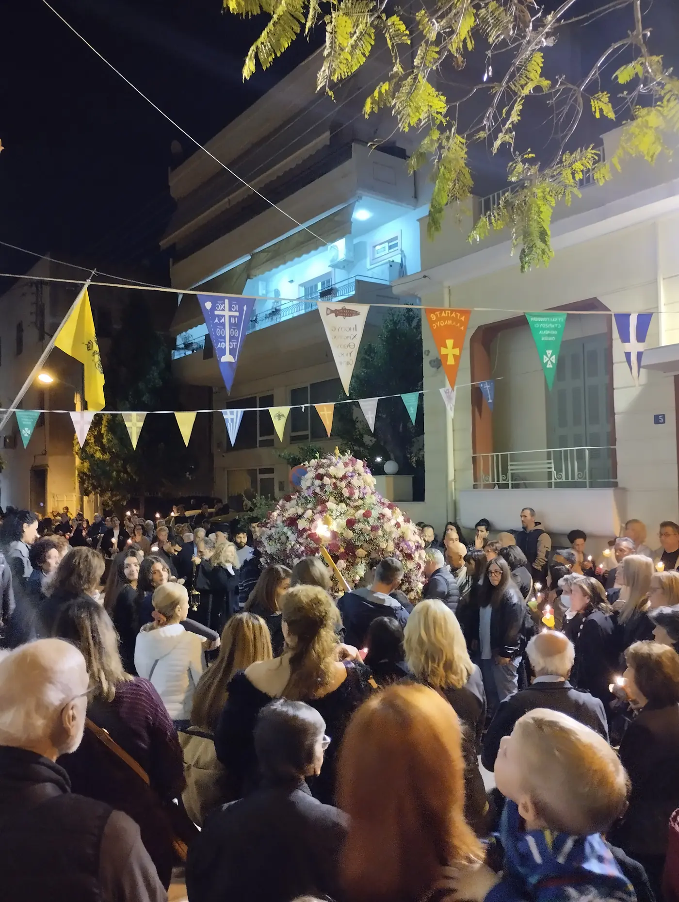 Une foule aux cierges allumés suit l’Épitaphe décoré dans une rue d’Athènes la nuit du Vendredi saint