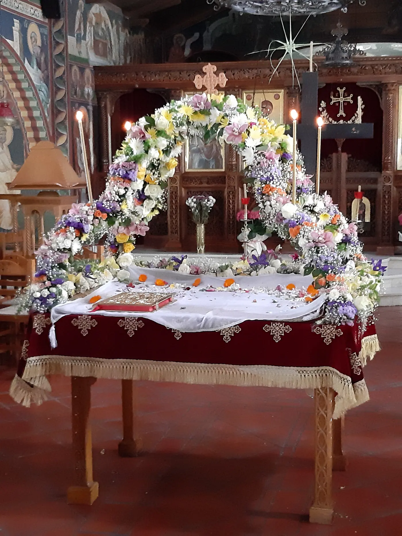 L’Épitaphe décoré d’une arche de fleurs blanches et rouges, dans une église devant l’iconostase