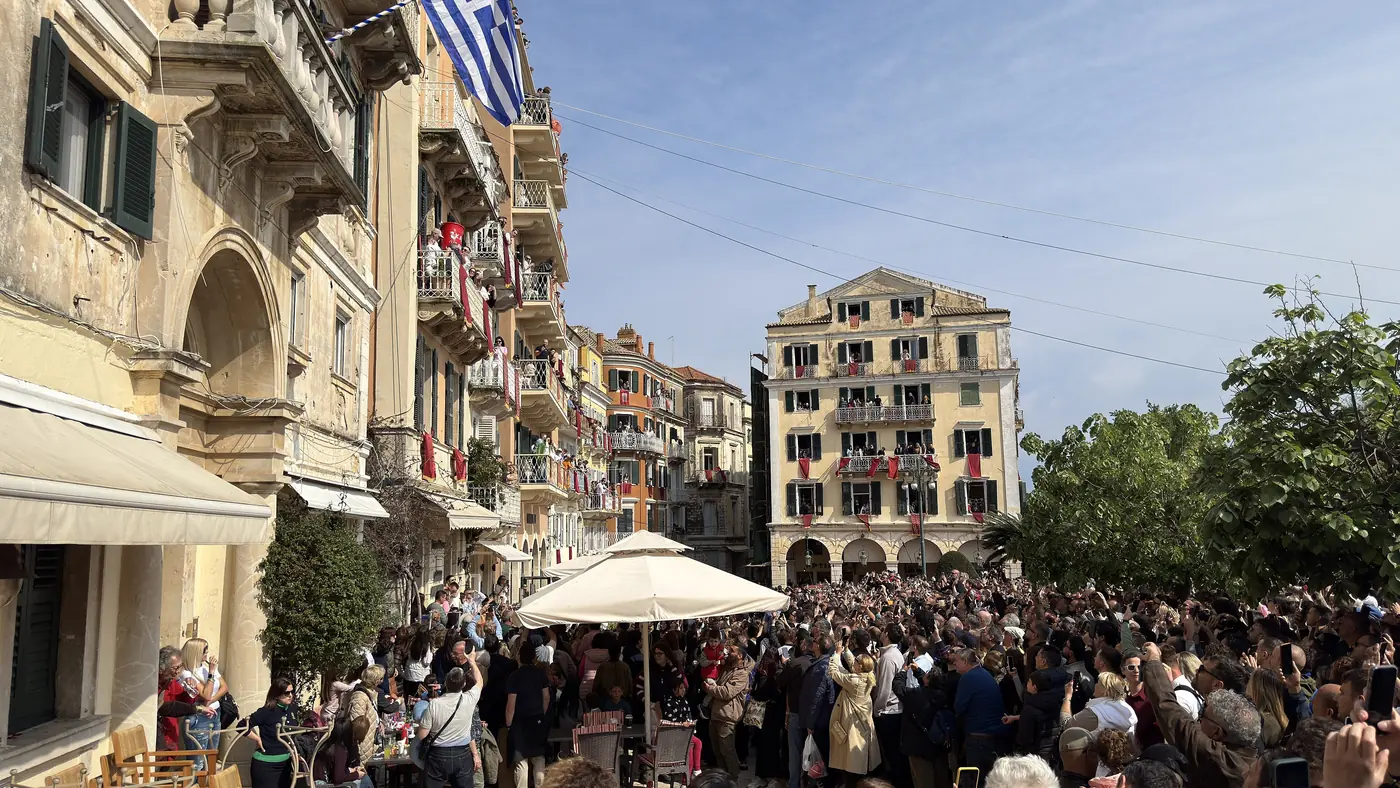 La foule sur la place Pentofanaro à Corfou regarde les balcons aux draps rouges avant la chute des cruches
