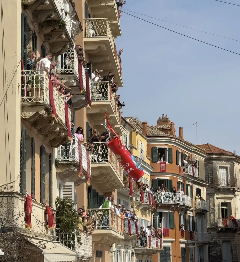 Une cruche rouge en terre cuite tombe du balcon d’un vieil immeuble de Corfou le Samedi saint, avec du monde en bas