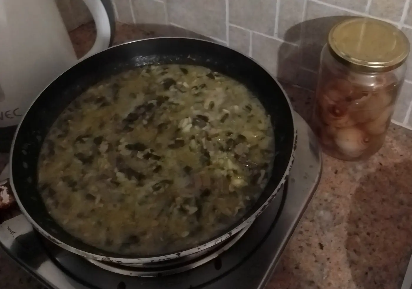 Une marmite de magiritsa, soupe verte aux abats d’agneau et aux herbes, à côté d’un bocal de bulbes