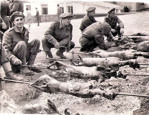 Photo en noir et blanc de 1958 : des soldats tournent des agneaux à la broche en plein air le dimanche de Pâques