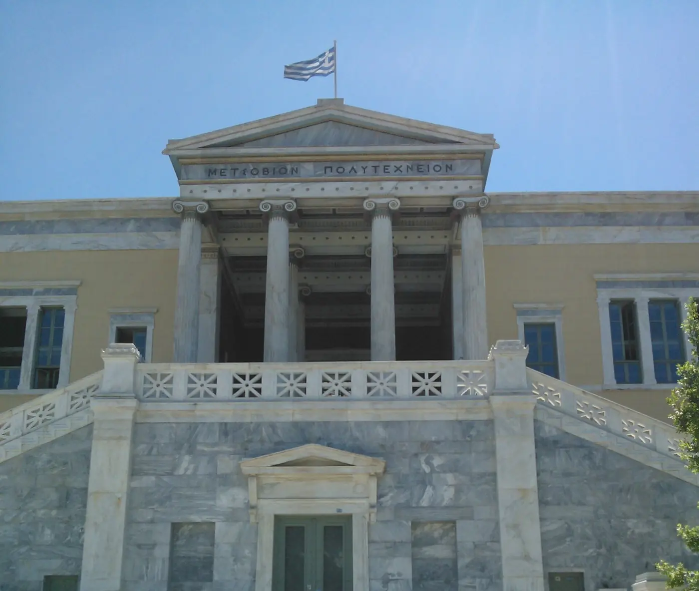 La scalinata di marmo e i propilei dell’edificio Averof con la bandiera greca sopra il frontone