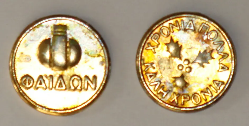 Die Münze der Vasilopita, eine goldene Münze mit dem Wunsch Chronia Polla, von beiden Seiten