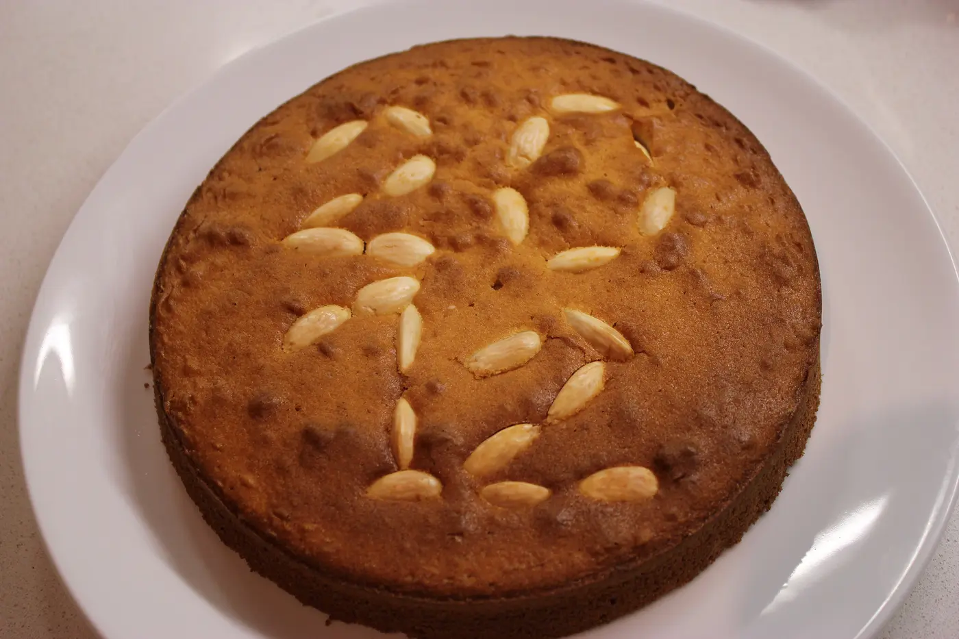 Eine mit Mandeln verzierte Vasilopita auf einem weißen Teller