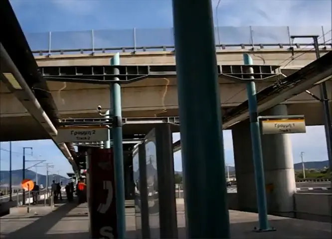 La estación de Koropi bajo el puente de la Attiki Odos, con andenes cubiertos y carteles