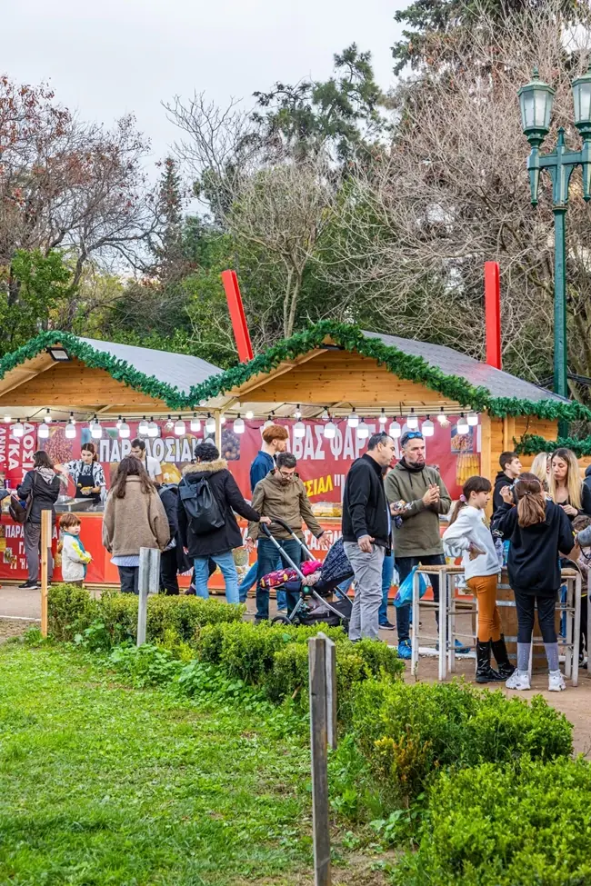 Houten kraampjes met slingers in Pedion tou Areos overdag, waar gezinnen met kinderwagens eten en snoep kopen
