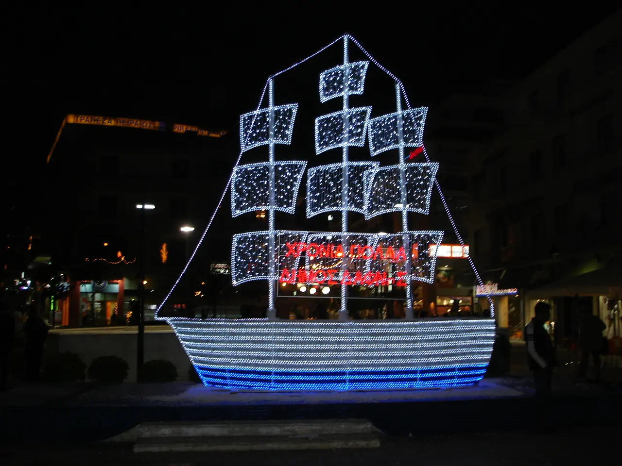 Groot lichtgevend kerstschip met zeilen van lampjes op een plein in Athene bij nacht