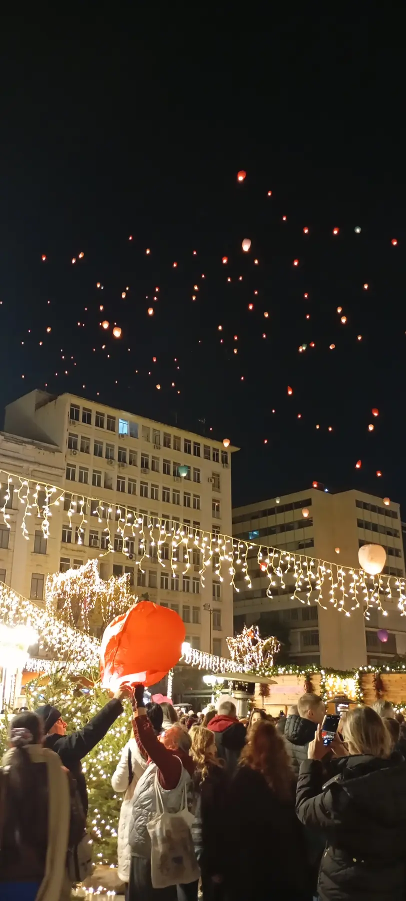 De verlichte draaimolen op het Kotziaplein met mensen ervoor en lantaarns in de lucht