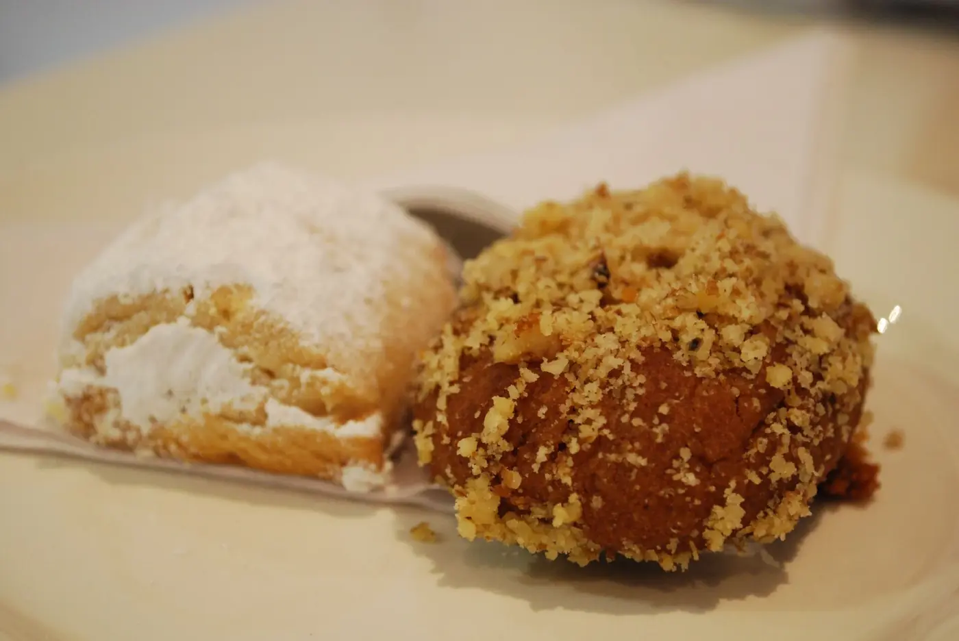 Een kourabies met poedersuiker naast een melomakarono met walnoten op een wit bord