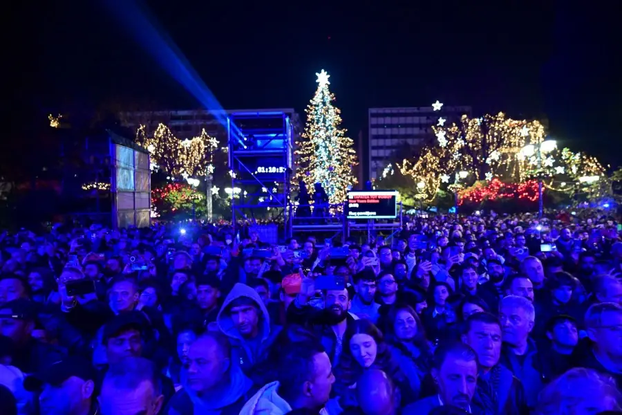 Menigte op het Syntagmaplein op oudejaarsavond, met de verlichte boom, schermen en schijnwerpers in de lucht