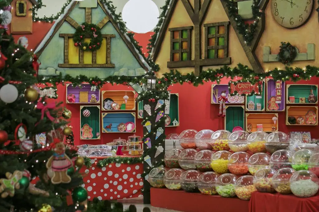 Kerstsnoepwinkel in de Christmas Factory, met doorzichtige potten vol snoep, versierde boom en geschilderde huisjes aan de muur