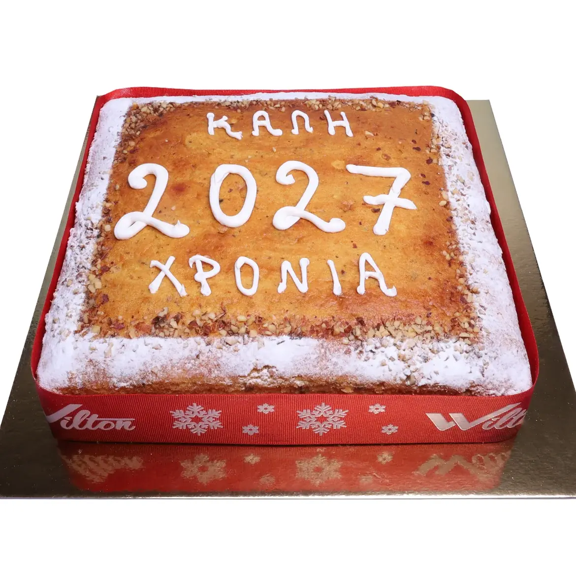 Vierkante vasilopita bestrooid met poedersuiker en walnoten, met de tekst „Kali 2027 chronia“ en een rood lint eromheen