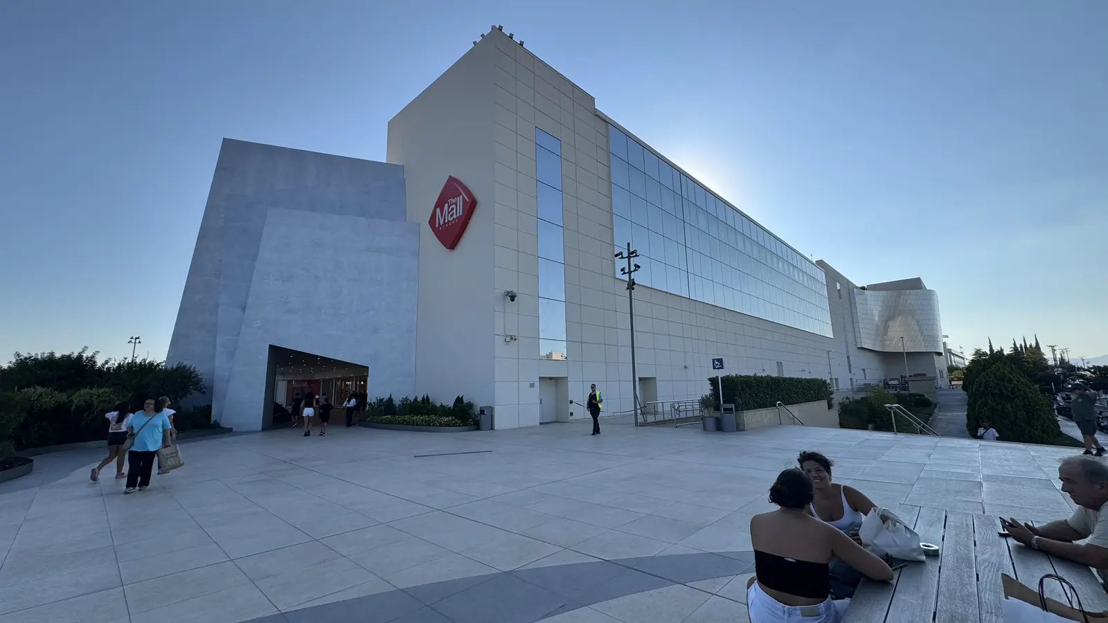 Widok na poziomy The Mall Athens ze schodami ruchomymi i witrynami sklepowymi