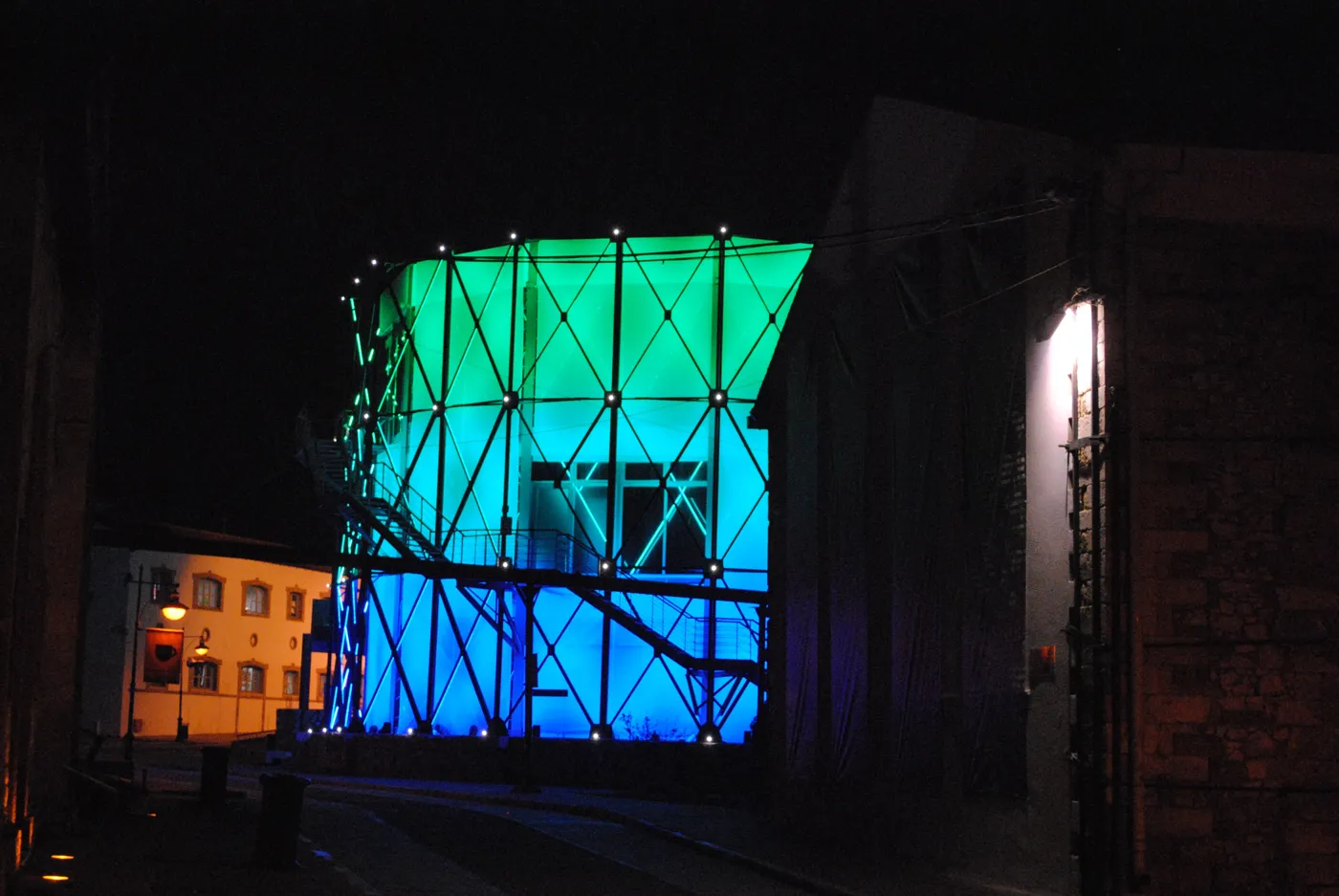 夜里被绿光和蓝光照亮的 Technopolis 储气罐
