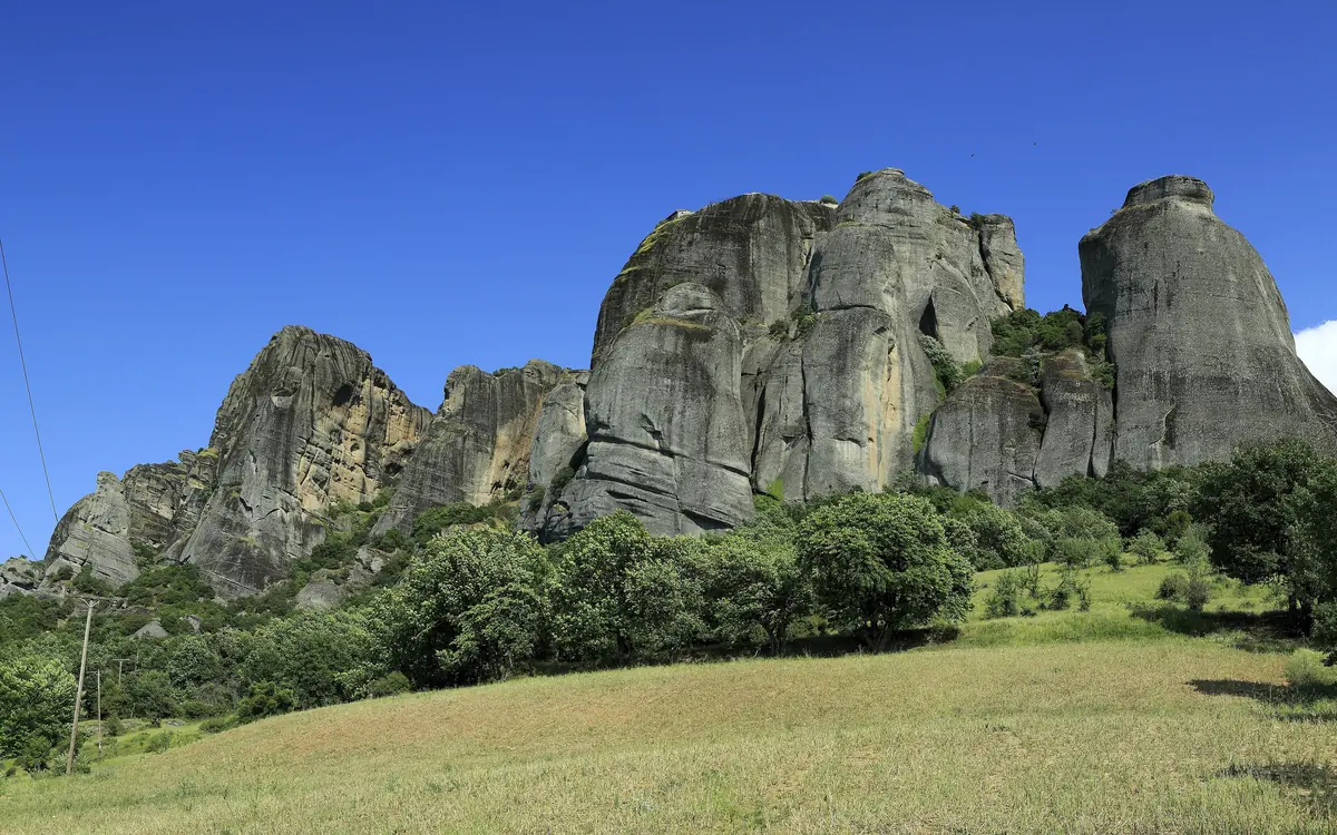 The Meteora rock pillars with a green meadow in the foreground