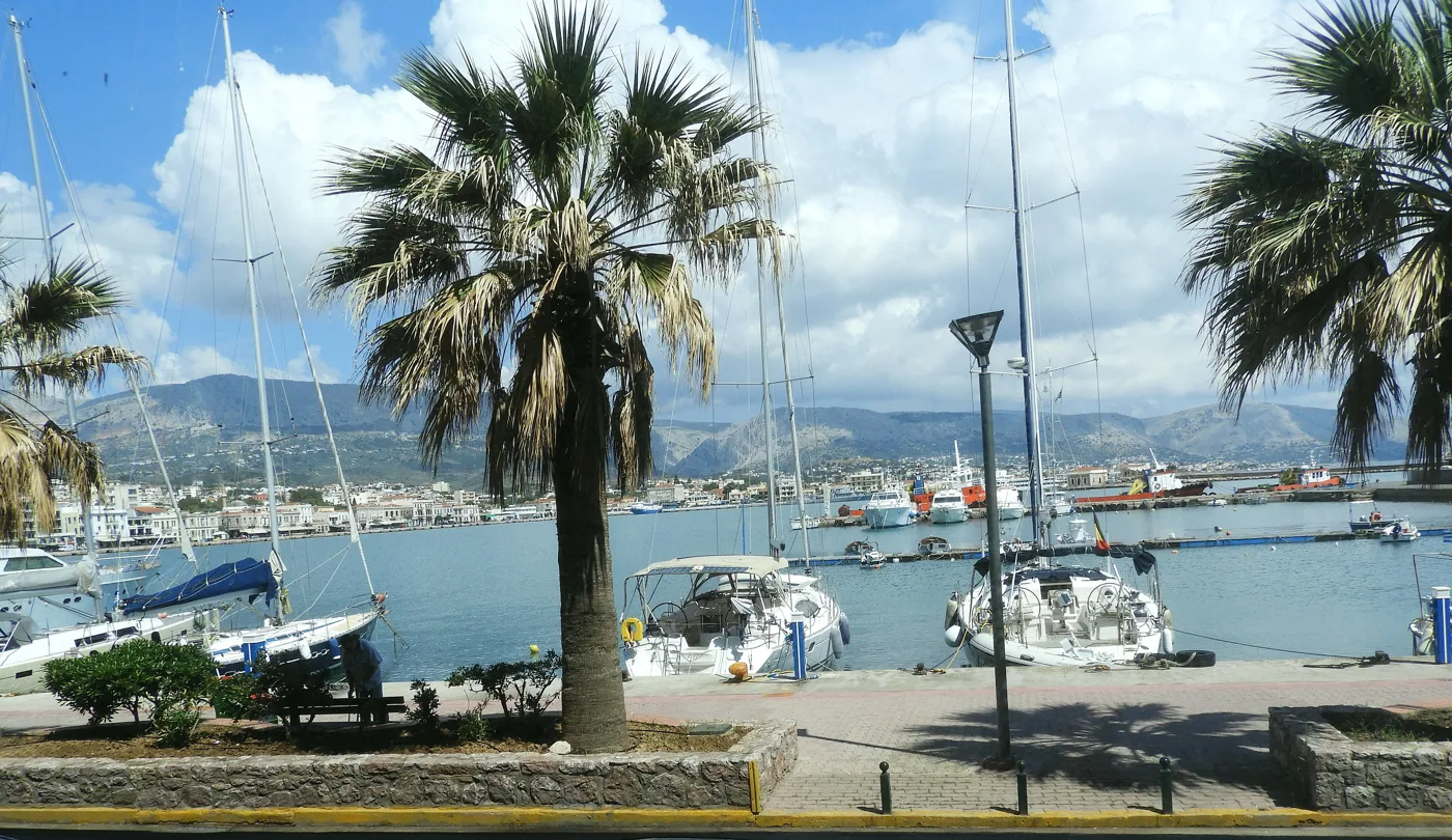 Port w Chios z żaglówkami, palmami i górami w tle
