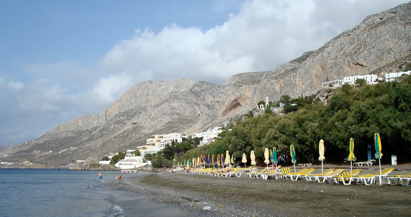 La playa de Masouri con sombrillas, bajo altos acantilados