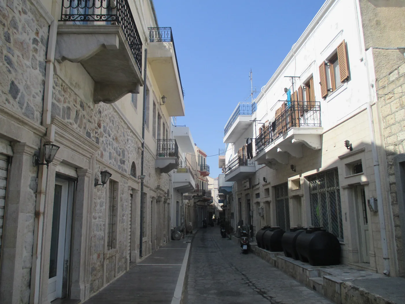Un callejón estrecho de Pothia con casas blancas y balcones
