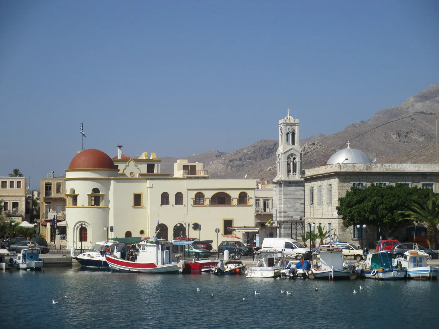 El puerto de Pothia con barcas de pesca y edificios neoclásicos de colores