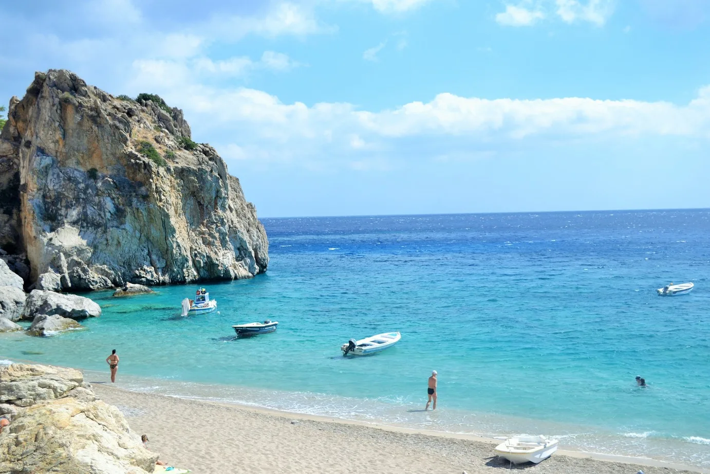 Kyra Panagia avec une eau turquoise, un grand rocher et des bateaux