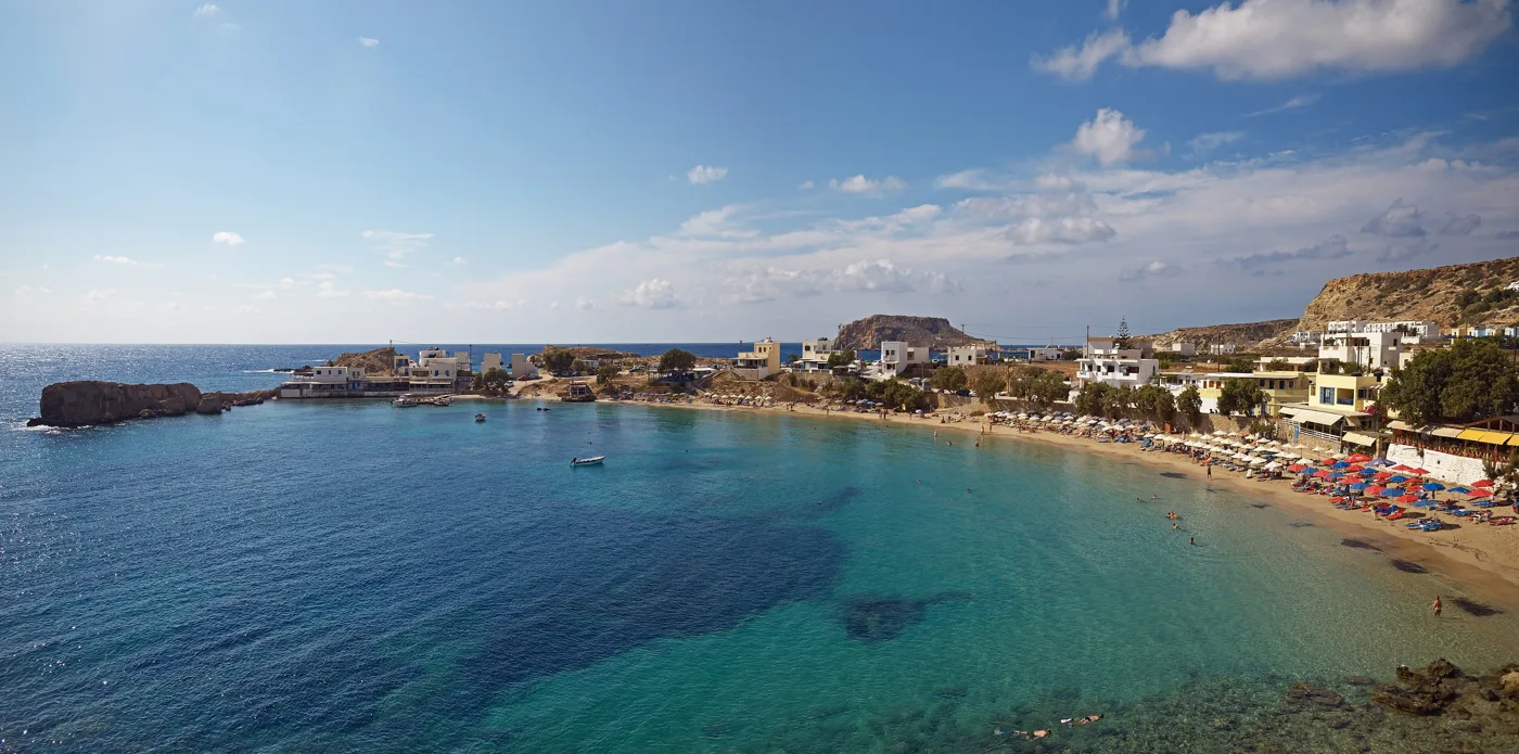 La baie de Lefkos avec une plage de sable et des maisons sur la côte ouest