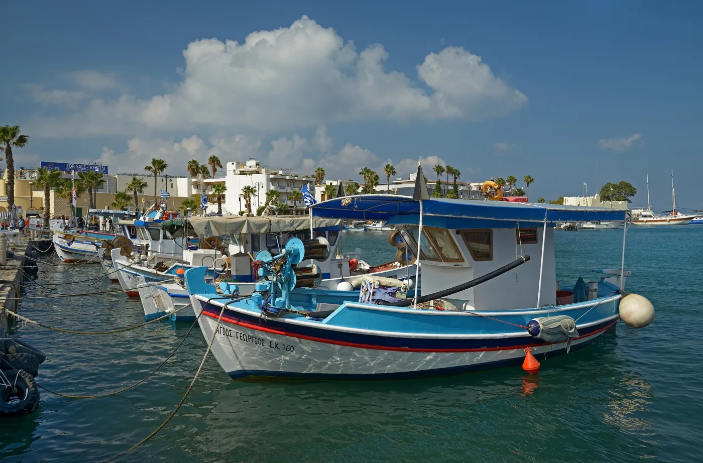 Barche da pesca colorate ormeggiate nel porto di Kos, con palme sul lungomare