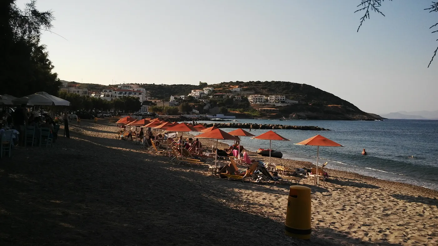 La plage d’Agia Pelagia l’après-midi, avec des transats, des parasols et du monde
