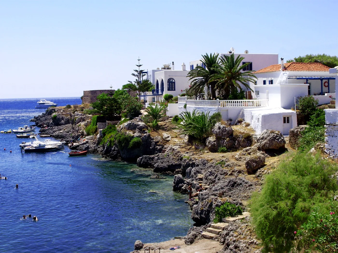 Des maisons blanches avec des palmiers sur les rochers d’Avlemonas, avec des bateaux dans l’eau