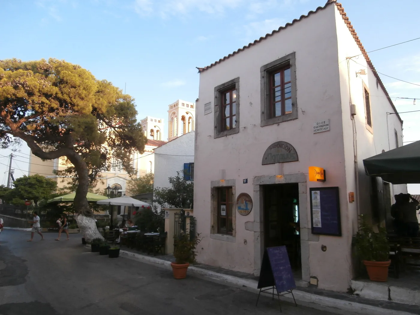 Un vieux café à deux étages avec un arbre devant, sur la place de Potamos