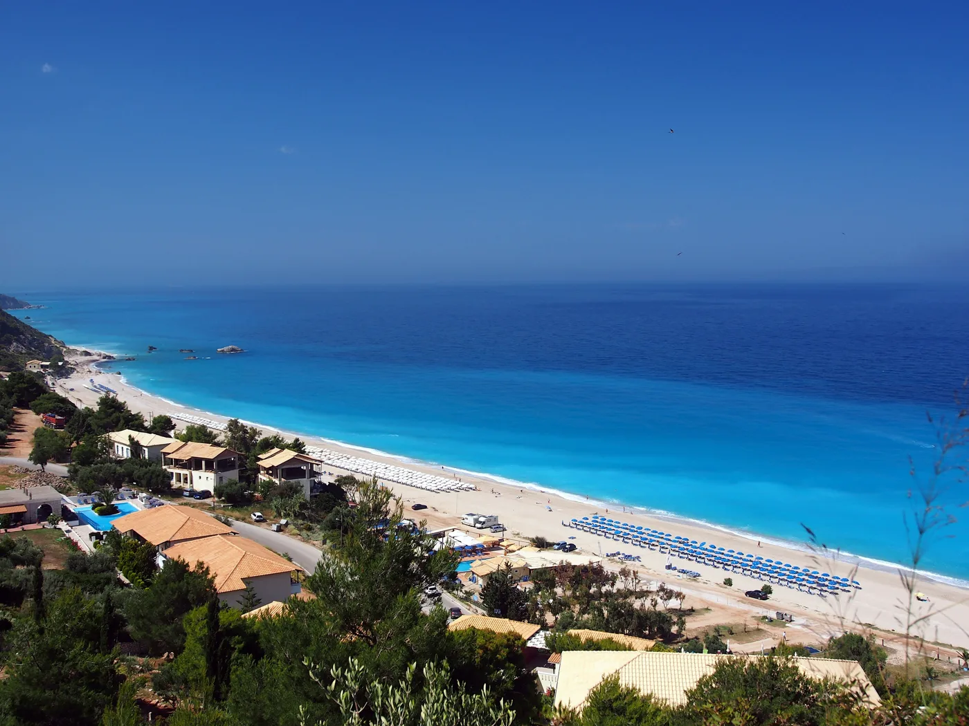 La longue plage de sable de Kathisma vue d’en haut, avec des transats et une eau bleu profond